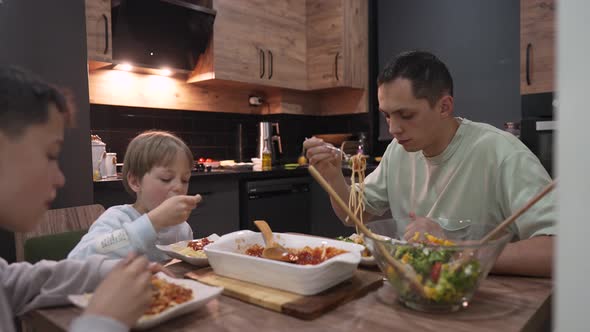 Young Happy Family Talking While Having Dinner at Home Table