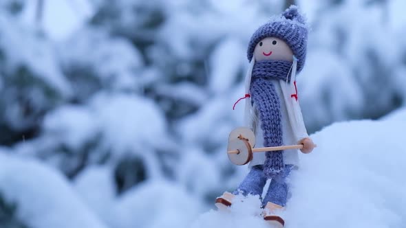 Angel Gnome in Scarf and Knitted Hat Skiing on Snowy Fir Branch Elf Toy on Skis in Snowy Landscape