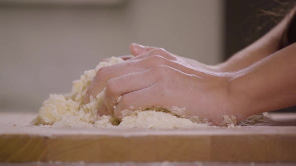 A Woman Kneads Crumbly Pastry Dough on a Kitchen Counter - Closeup - Slow Motion