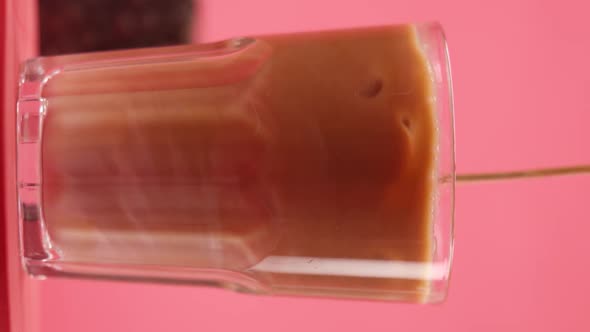 Vertical video: Stir ice latte in a glass