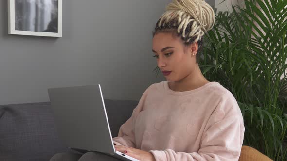 Young Woman Student Working on Laptop on Sofa at Home