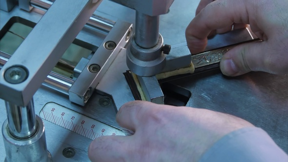Craftsman working on frame, glue together pieces in special machine
