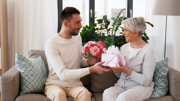 Son Giving Present and Flowers To Senior Mother