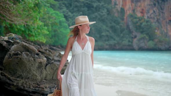 Woman Walks on the Tropical Paradise Beach Lagoon She Wears White Dress Hat and a Bag
