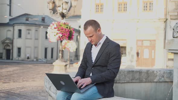 Portrait of a Man Working at a Laptop in the Old City Street of Lviv