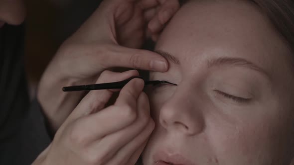 Girl is Doing Makeup Drawing an Arrow on Her Eyes