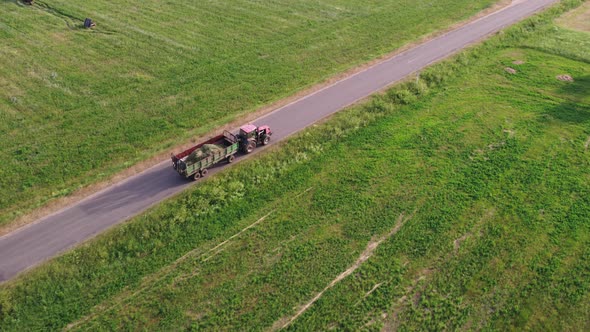 Tractor Carries a Trailer with Hay Through the Countryside