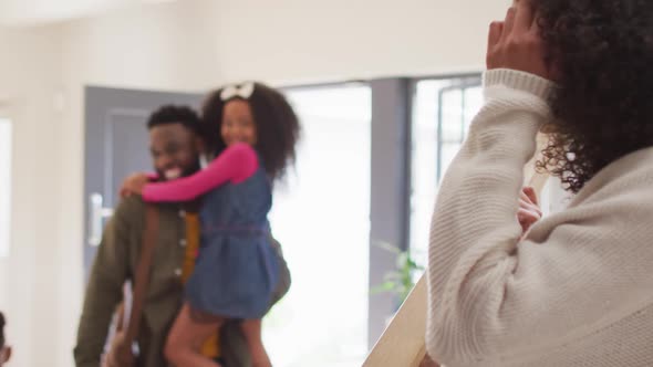 Happy african american father coming back home, hugging with children and smiling to wife