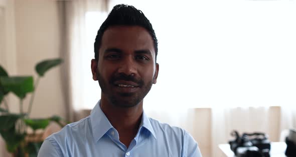 Indian man smiling on camera inside modern office