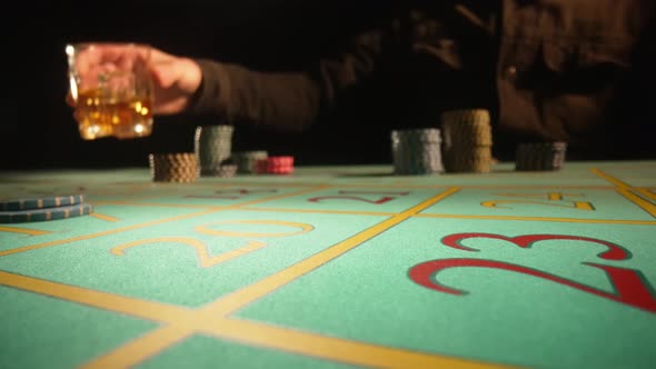 Unrecognizable Male Gambler Makes Bets While Sitting at Roulette Table in Casino