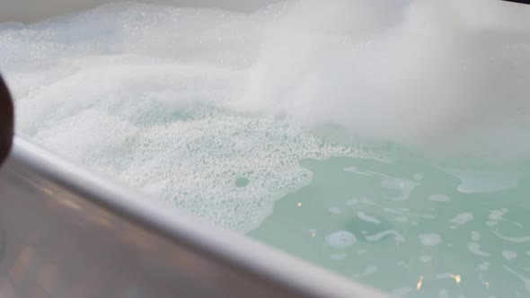 African american woman getting into bath with one leg in bathroom