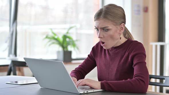 Young Woman Reacting To Loss on Laptop in Office 