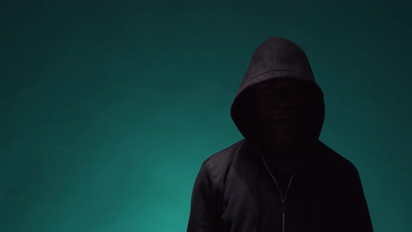 Portrait of computer hacker in hoodie. Obscured dark face.