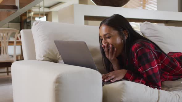 Mixed race woman on couch at home using laptop having video chat