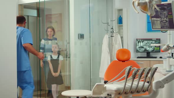 Man Nurse Inviting Kid Patient in Consultation Dental Room