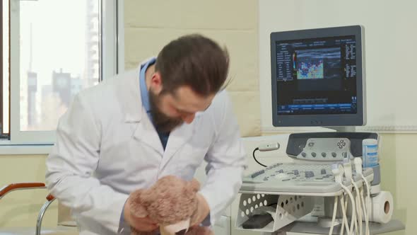 Friendly Male Pediatrician Holding Teddy Bear Toy Waving To the Camera