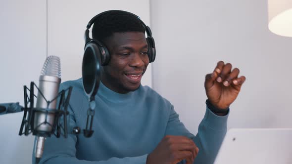 Man Wearing Headphones Taking an Online Using a Laptop and Microphone