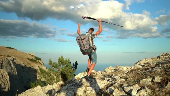 Male Hiker in Backpack and Trekking Poles Reaching Up Top of Mountain Hike Travel and Raise Hands