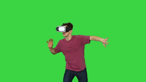 Amazed Man Using VR Headset Glasses Touching and Interacting with Virtual Reality World on a Green