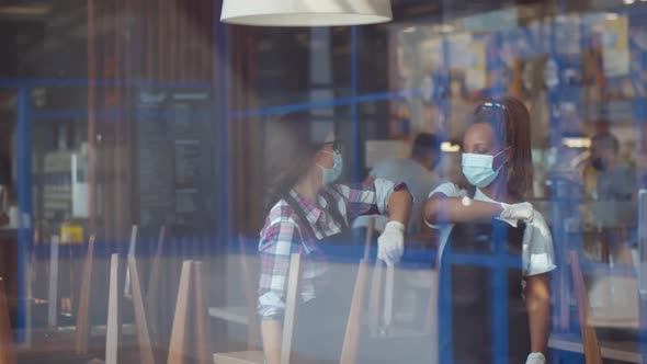 Multiethnic Waitresses in Protective Masks and Gloves Doing Elbow Bumps Greeting