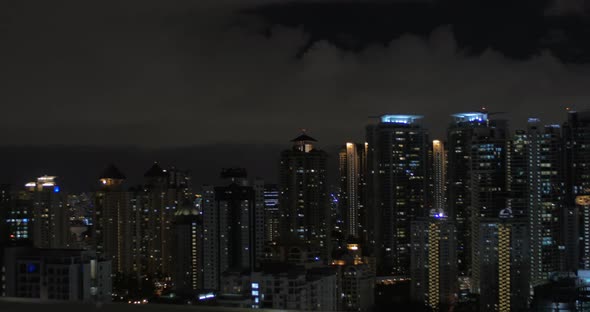 In Kuala Lumpur, Malaysia seen night city and pool on roof with woman working on tablet