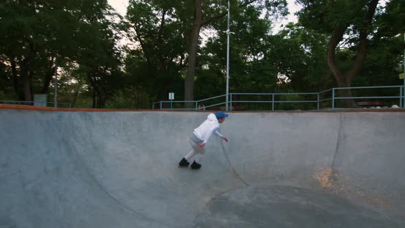 Aggressive Inline Roller Skater Doing Tricks in Concrete Skatepark Outdoors During Sunset