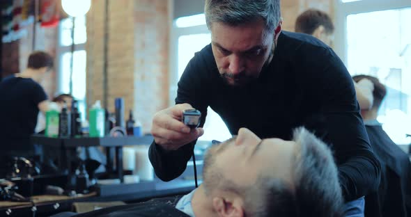 Man Has a Beard Cut in a Stylish Barber Shop