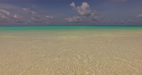 Tropical flying copy space shot of a sandy white paradise beach and blue sea background in vibrant 4