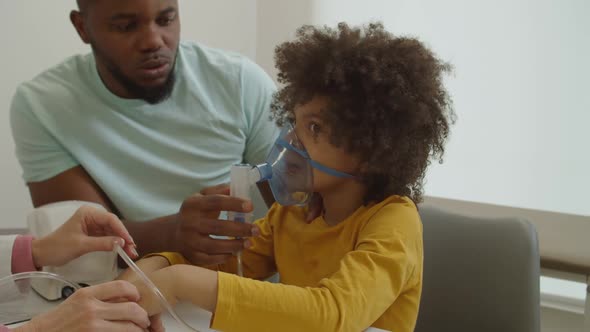 Sick Elementary Age Black Boy Wearing Mask Nebulizer Inhaling Vapor Medication at Hospital
