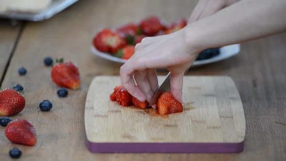 Woman is cutting fresh organic strawberry on the cutting board