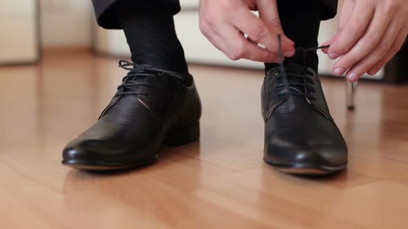 Man Ties Up Shoelaces on Black Leather Shoes