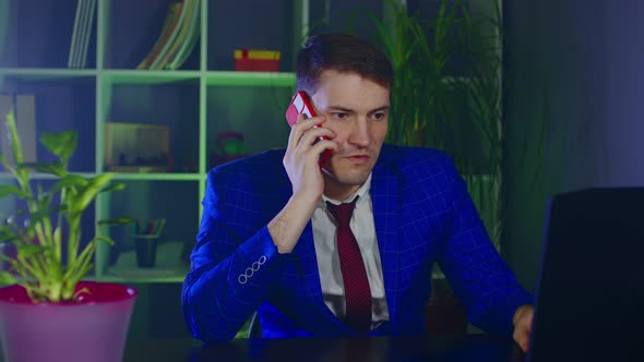 Young Man Talks on Mobile Phone Sitting in Office