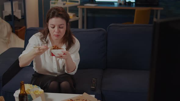 Person Eating Asian Noodles with Chopsticks on Couch