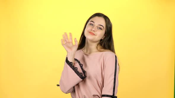 Young Girl Waving with Hands on Yellow Background