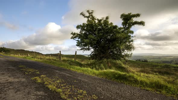 Time lapse of rural landscape with grass fields and hills during a cloudy day in Ireland. alt