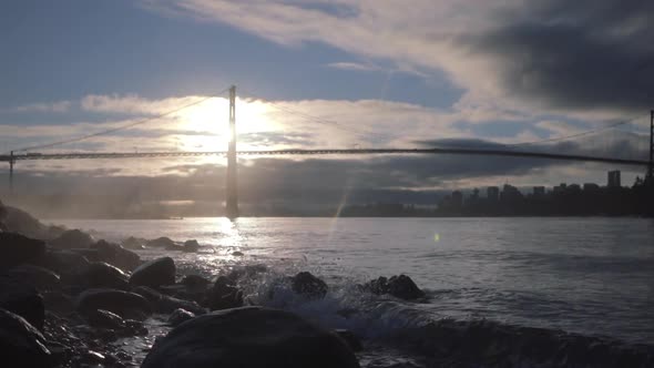 Morning ocean waves splashes rocks with Lioins Gate bridge in background