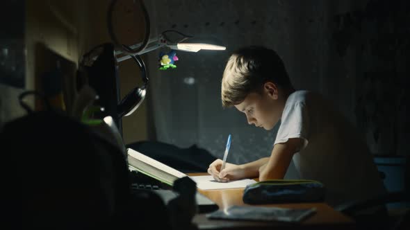 Young Male Child is Very Concentrated Doing His Homework at Desk in His Room