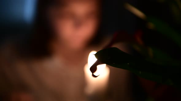 4k The girl looks at a burning candle, close-up