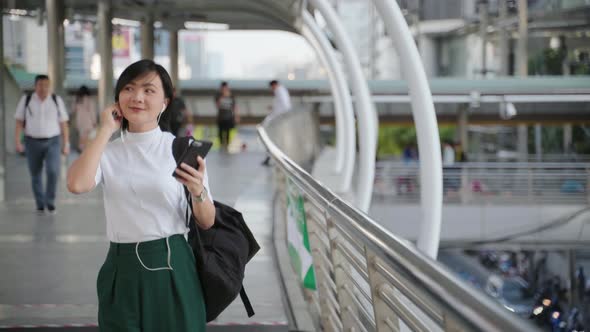 Portrait of happy asian woman with earphone listening music and using smartphone dance