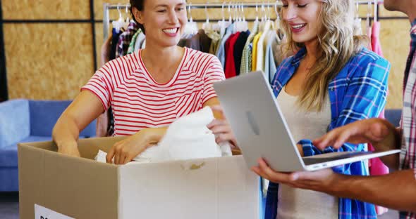 Man working on laptop while volunteers sorting clothes of donation box