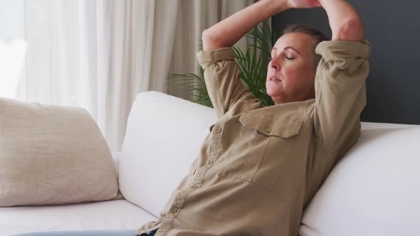 Tired caucasian senior woman lying on the couch at home