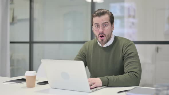 Young Businessman Feeling Shocked While Using Laptop in Office