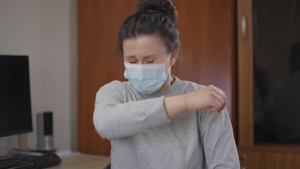 Medium Shot of Young Ill Woman Sneezing Looking at Camera Sitting Indoors