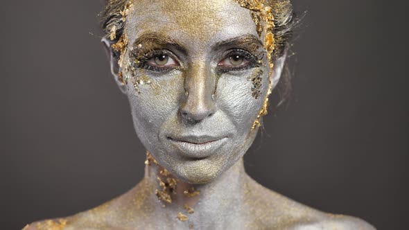 Beautiful Young Female Model with Gold and Silver Paint on Her Skin and Hair in the Studio