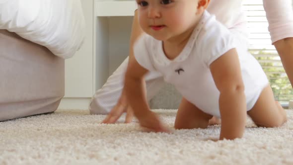 Mother helping her Baby girl Crawl alt