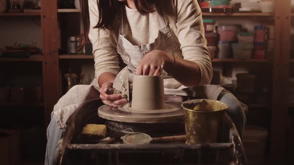 Pottery Workshop  Female Hands Smoothening the Sides on the Pot Using a Tool