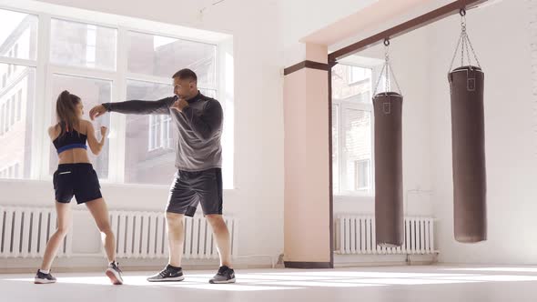 An Experienced Trainer Puts the Technique of Blows To a Young Girl in the Boxing Hall