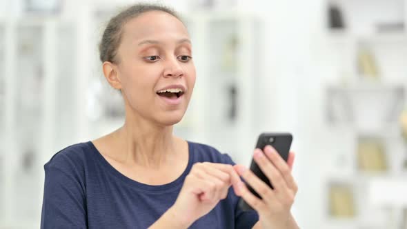 Portrait of Excited African Woman Celebrating Success on Smartphone