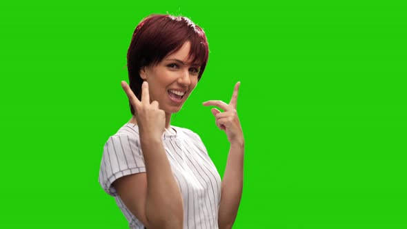 Portrait of happy woman showing victory sign on green background