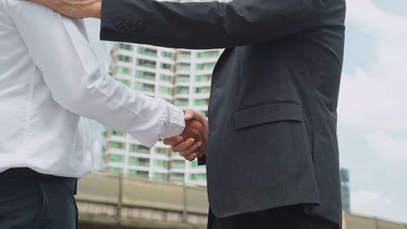 Close up shot, Asian business men partnership making handshake in the city building in background.